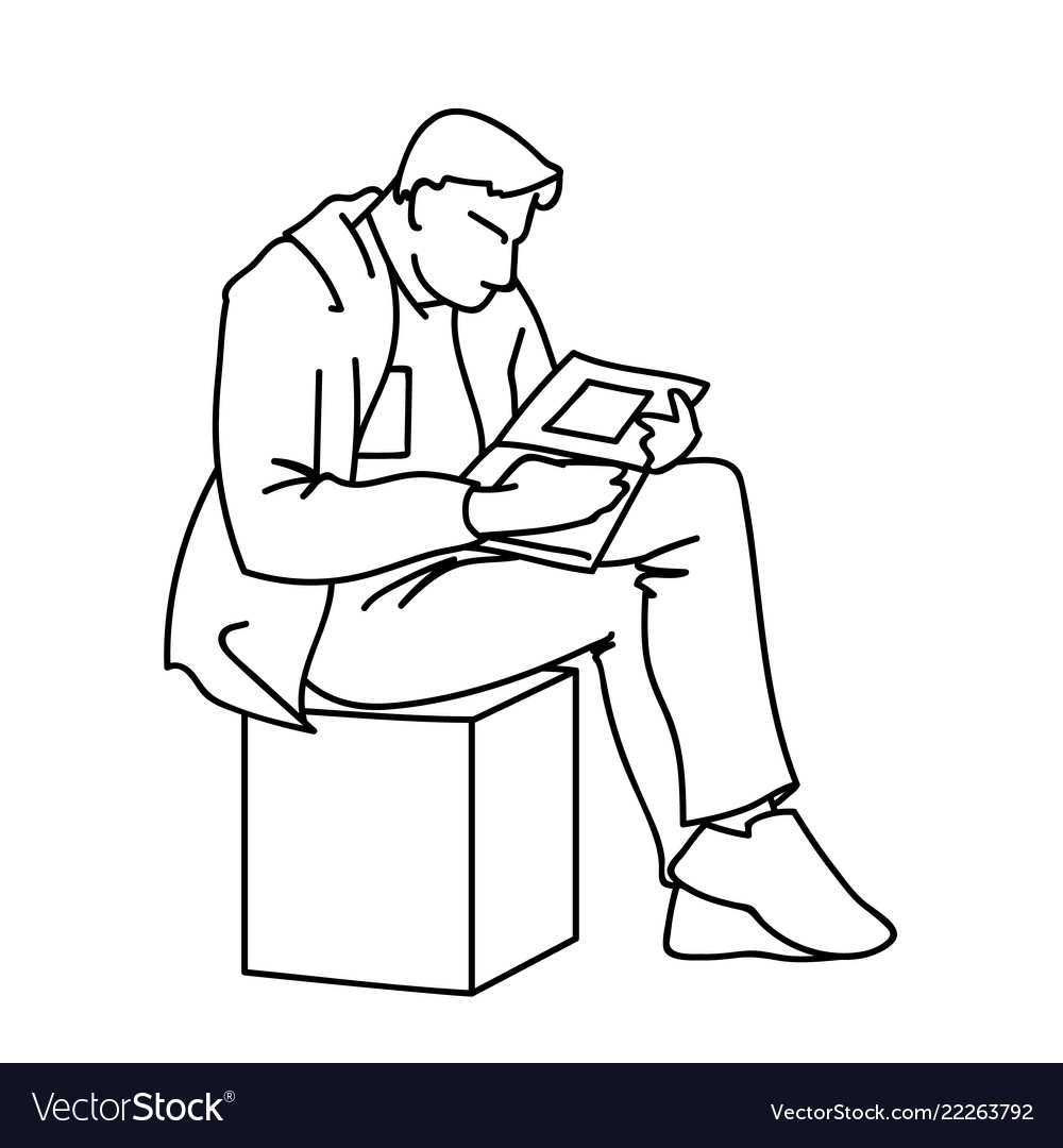 An adult man is reading a book sitting on cube