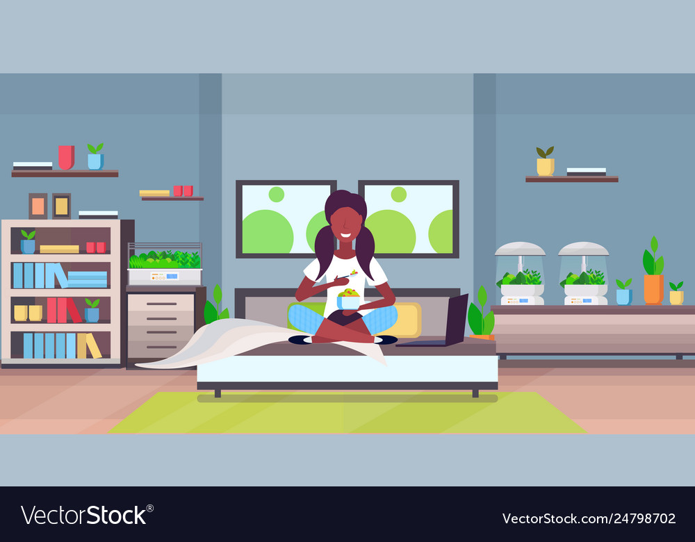 African girl sitting on bed eating fresh fruits